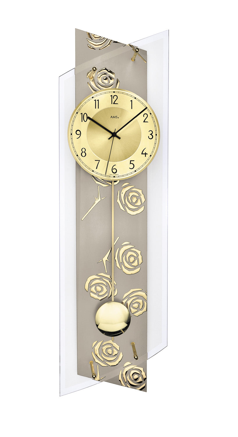 Horloge murale avec décor de roses, cadran doré et poids de pendule dans un boîtier en verre