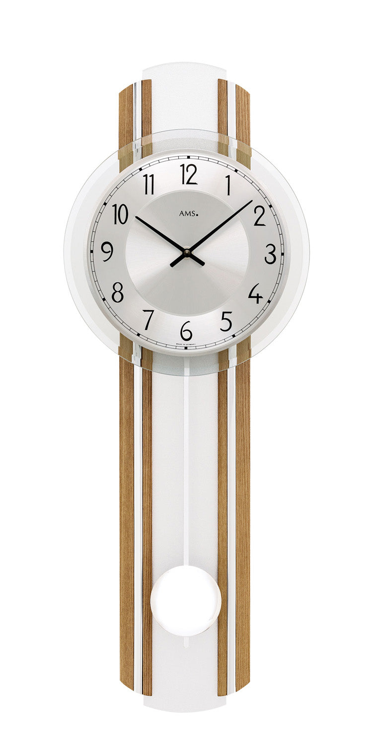 Horloge murale avec cadran blanc, lamelles en chêne huilé et mouvement à pendule derrière verre minéral.
