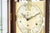 Gros plan du cadran d'une horloge de parquet avec chiffres romains et ornements dorés