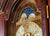 Extrait du cadran d'une horloge de parquet avec segment bleu, ornements décoratifs et chiffres romains