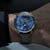 Montre pour homme au poignet : cadran bleu, bracelet en cuir marron, boîtier argenté