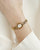 Goldfarbene Armbanduhr am Handgelenk mit geriffelter Lünette und Metallgliedern