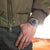 Herrenuhr am Handgelenk mit blauem Zifferblatt und Edelstahlarmband.