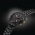 Schwarze Herrenarmbanduhr mit Metallband, goldfarbenen Drückern und drei Hilfszifferblättern