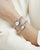Zwei Damen-Armbanduhren am Handgelenk, silbernes Edelstahlarmband, ovales Gehäuse, weißes Zifferblatt