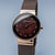 Montre pour femme avec cadran bordeaux, index bâtons et boîtier couleur or rose ; bracelet milanais.