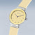 "Montre femme : cadran jaune, aiguilles noires, bracelet beige, couronne argentée"