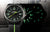 Montre homme avec cadran noir et index luminescents verts, bracelet textile noir