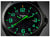 Montre homme en gros plan : logo traser, cadran noir avec chiffres luminescents verts