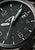Montre bracelet pour homme avec cadran noir, index verts et inscription Traser.