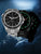 Bracelet de montre argenté pour homme avec cadran noir et index lumineux verts