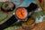 Herrenarmbanduhr mit orangefarbenem Zifferblatt, schwarzem Band und geriffelter Lünette.