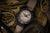 Montre pour homme avec bracelet textile beige, lunette noire et cadran beige.