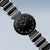 Montre pour femme avec cadran noir et bracelet en métal, vue de côté en biais.