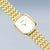 Montre femme en angle : boîtier doré, cadran blanc et bracelet en métal.