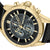 Herrenchronograph im Detail: schwarzes Zifferblatt, goldfarbene Lünette, Lederarmband