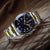 Herrenarmbanduhr auf Leder: bicolor Stahl/Goldfarben, blaues Zifferblatt mit grünen Leuchtanzeigen