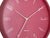Gros plan d'une horloge murale rouge : aiguilles blanches et centre de l'horloge