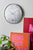 "Silver round wall clock with mosaic dial and black hands"