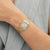 Goldfarbene Damenarmbanduhr mit rechteckigem Zifferblatt, römischen Ziffern und Gliederarmband.
