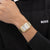 Goldfarbene BOSS-Armbanduhr mit rechteckigem Zifferblatt und Gliederarmband am Handgelenk