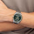 Herrenarmbanduhr BOSS am Handgelenk mit grünem Zifferblatt und silbernem Armband.