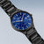Montre homme avec cadran bleu et bracelet en titane noir, vue latérale