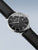 Herrenuhr mit schwarzem Zifferblatt, silbernen Zeigern und schwarzem Lederarmband