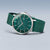 Montre homme portée en biais : cadran vert, boîtier argenté, bracelet milanais vert