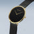 Montre pour femme avec cadran noir, boîtier doré, couronne, bracelet milanais noir.