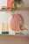 Horloge murale avec cadran rayé orange et blanc et cadre beige sur le mur