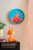 Horloge murale sur un mur clair avec un cadran bleu et un motif de poisson rouge