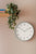 Horloge murale au mur : cadre turquoise, cadran blanc, chiffres noirs