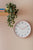 Horloge murale avec un cadre rond rose flamant et un cadran blanc.