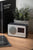 Radio-réveil FM noir avec haut-parleur, écran et antenne sur surface en bois