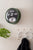 Horloge murale ronde sur un mur avec un cadre vert, un dateur à chiffres basculants et un affichage des aiguilles