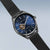 Herrenarmbanduhr mit blauem Zifferblatt und schwarzem Milanaise-Armband, seitliche Ansicht