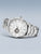 Silberne Herrenuhr mit weißem Zifferblatt, sichtbarem Automatikwerk und Metallarmband