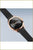Montre femme, vue de biais : cadran noir, boîtier or rose, bracelet en métal noir