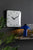 Horloge murale carrée au mur : cadran blanc avec aiguilles noires
