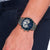 Herrenarmanduhr am Handgelenk: blaues Zifferblatt mit Analoguhr-Zählern, Edelstahlgliederarmband