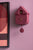 Horloge murale design nichoir, version rouge foncé avec aiguilles et pendule ronde au mur.
