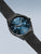 Herren-Uhr mit schwarzem Milanaise-Armband und blauem Zifferblatt, seitliche Ansicht
