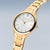 Montre femme dorée en gros plan : cadran blanc, couronne, bracelet à maillons