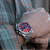 Herren-Armbanduhr am Handgelenk mit silbernem Band und rotem Chronograph-Zifferblatt