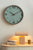 Horloge murale avec cadran gris-vert et cadre aspect bois au mur
