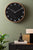 Grande horloge murale Karlsson au mur : cadran noir avec bordure et aiguilles effet bois