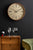 Horloge murale sur un mur avec un cadre en bois couleur sable et un cadran de couleur crème.