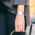 Damenarmbanduhr am Handgelenk mit silbernem Mesh-Armband und weißem Zifferblatt