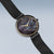 Montre pour femme avec cadran rond foncé et aiguilles dorées, bracelet milanais